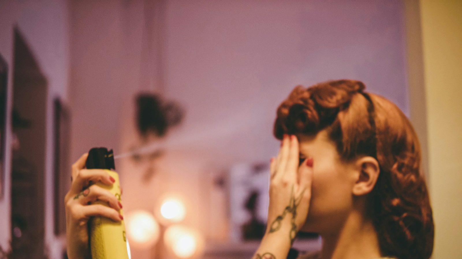 Woman spraying hairspray on a vintage curled hairstyle