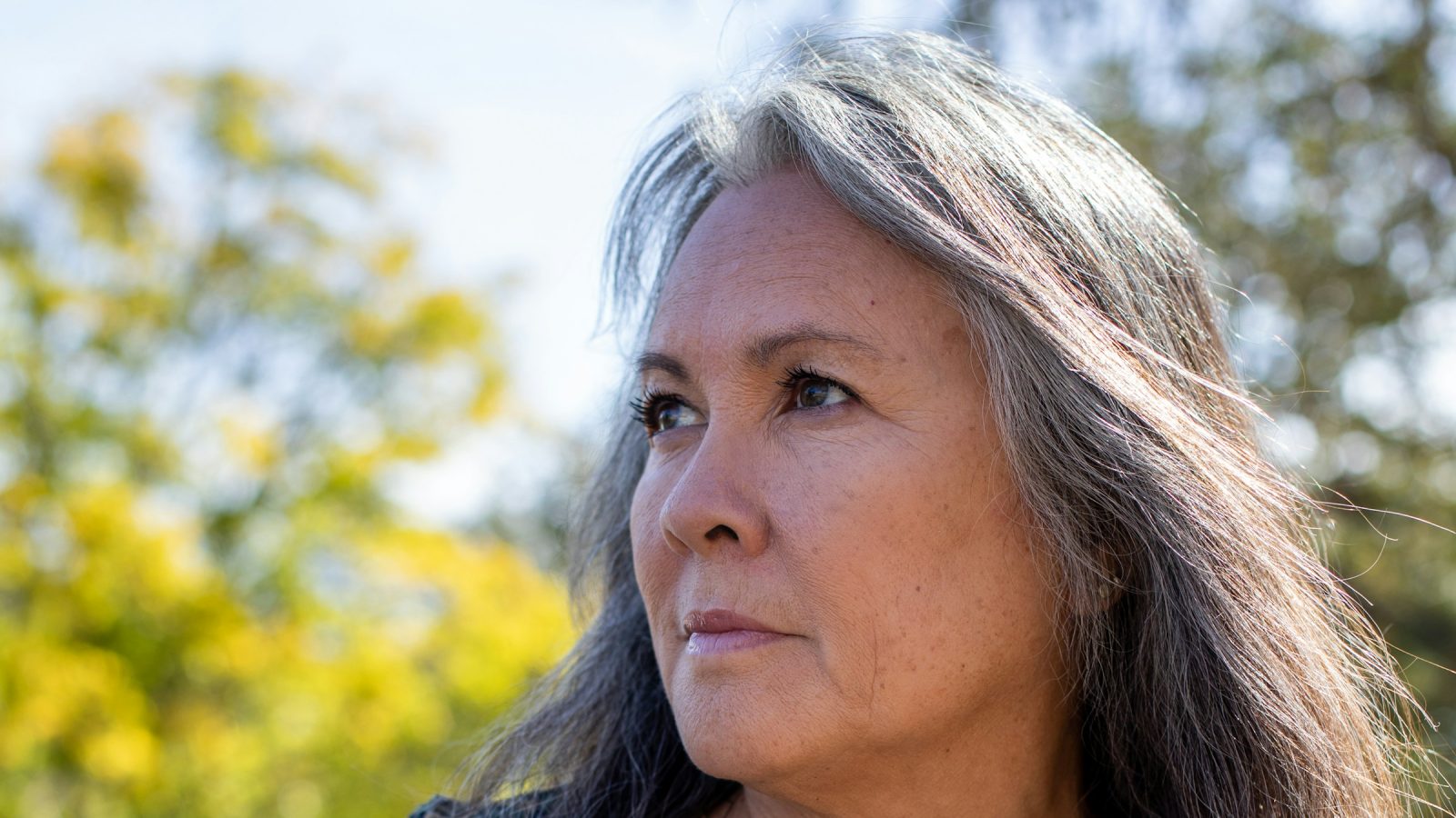 Woman with long salt-and-pepper gray hair outdoors
