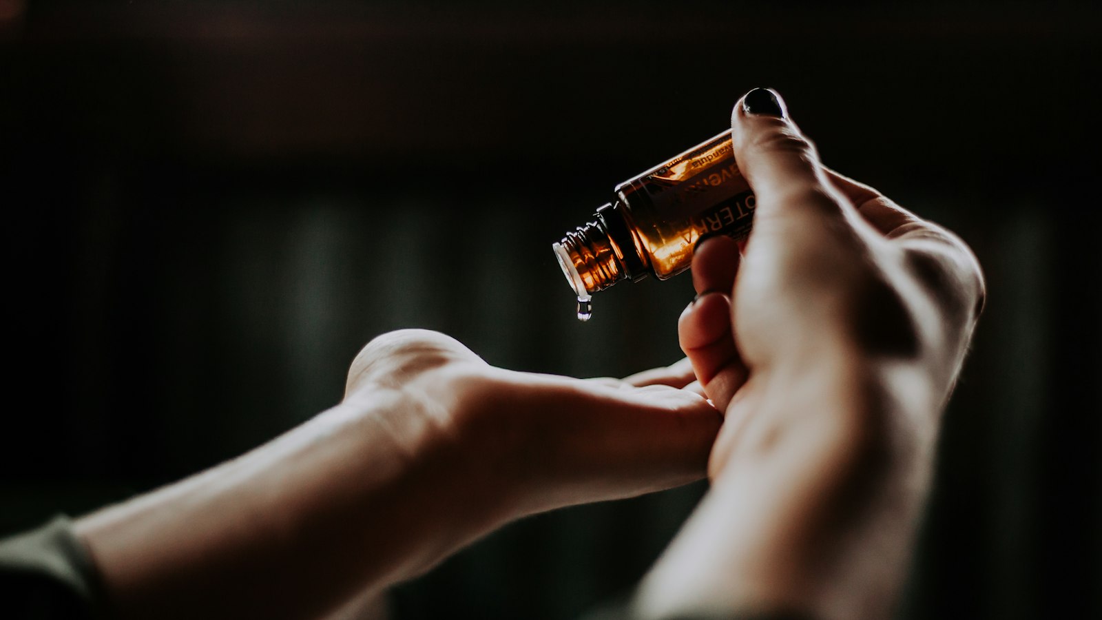 Hand holding an amber dropper bottle of hair oil